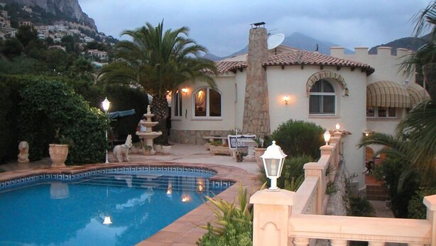 A pool area with a stone building, a mountain in the background, and a clear sky. - "La Favorita: Mountain Serenity with Ocean Views". (Calpe)