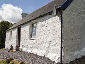 A white house with a stone foundation, a window, and a satellite dish. - 1 bedroom accommodation in Strontian (Strontian)