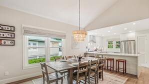 A modern kitchen with a large island, white cabinetry, and a hanging light fixture.