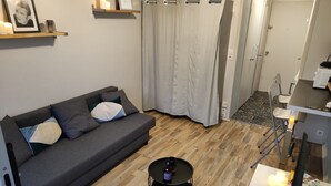 Uma sala de estar moderna com um sofá cinzento, uma mesa redonda pequena e chão de madeira.