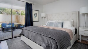 Een slaapkamer met een bed, nachtkastjes, een plafondventilator, een raam met gordijnen en uitzicht op de omgeving.