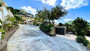 A residential area with a concrete driveway leading to a modern house with a balcony.