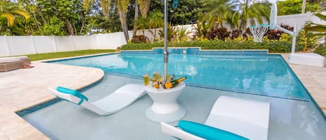 A swimming pool with lounge chairs and a tiki umbrella.