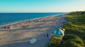 A beach with a lifeguard tower, umbrellas, and people.