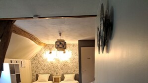A cozy bedroom with a loft-style ceiling, a bed with floral-patterned pillows, a bench, and a wardrobe. - Le clos verdonnais  (Verdon)