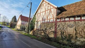Une maison traditionnelle à colombages, avec un toit recouvert de tuiles rouges et des murs couverts de lierre.