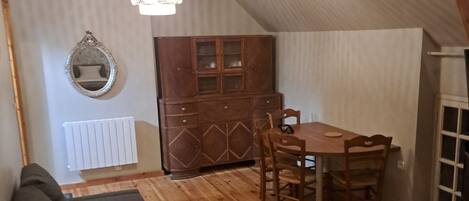 A cozy attic bedroom with a loft bed, a wooden dining table, and a built-in cabinet.