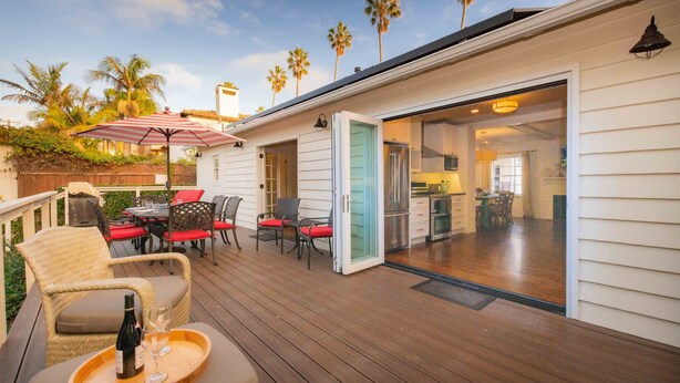 A deck with outdoor furniture, a dining area, and a sliding glass door leading to a kitchen. - Pool/Hot Tub/Pet Friendly/Walk To Beach (La Jolla)