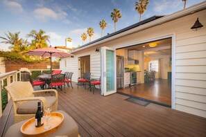 A deck with outdoor furniture, a dining area, and a sliding glass door leading to a kitchen.