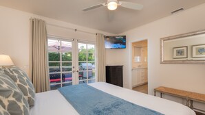 A hotel room with a bed, a ceiling fan, a TV, a bench, and a view of the outside. - Pool/Hot Tub/Pet Friendly/Walk To Beach (La Jolla)