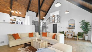A spacious living room with a high ceiling, a staircase, and a cozy seating area.