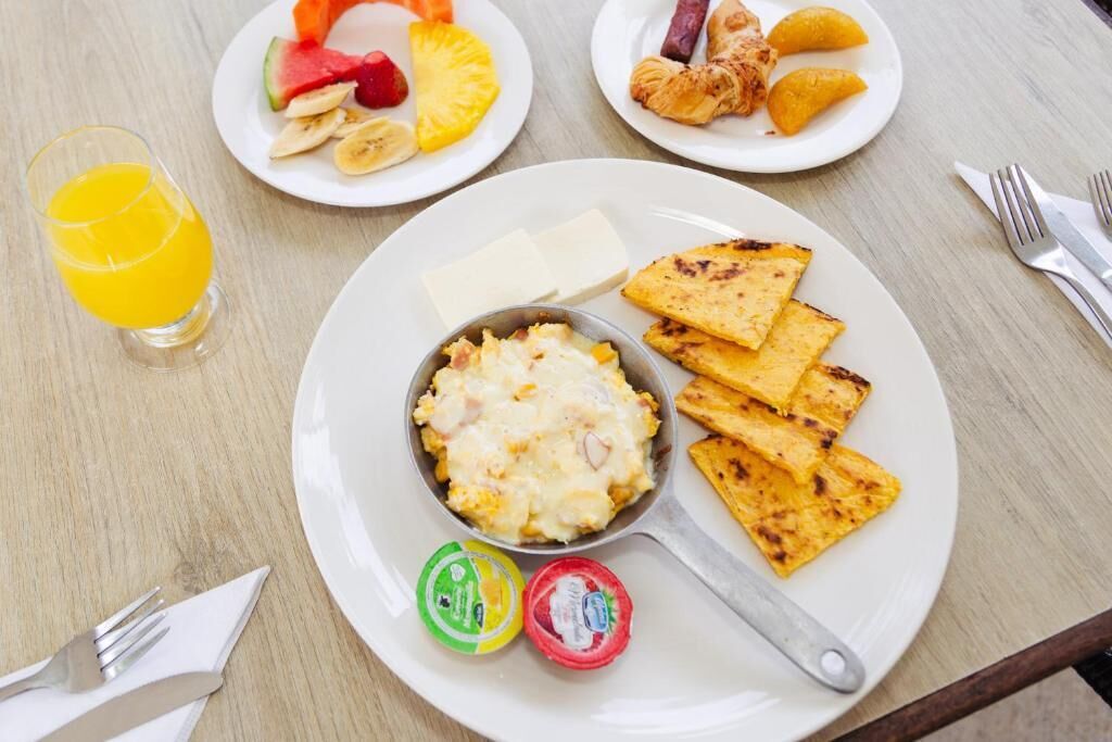Desayuno con tostadas, fruta y un cuenco de huevos revueltos.