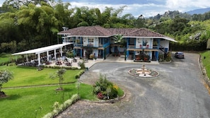A two-story building with a covered patio area, a central fountain, and a landscaped garden. - HOTEL HACIENDA SANTA CLARA (Santa Rosa de Cabal)