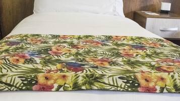 Una cama con un edredón estampado con motivos florales, un cabecero de madera y una almohada blanca.