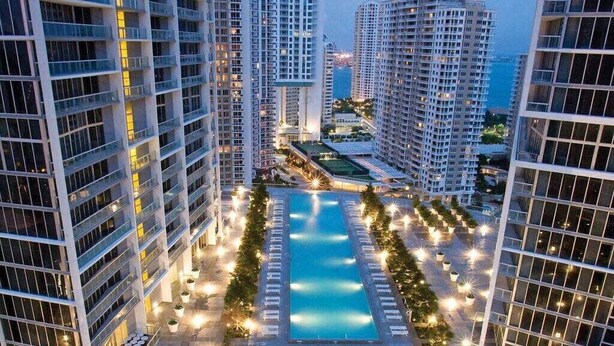 Un hotel de gran altura con un patio central, varios balcones y vistas a la ciudad circundante.