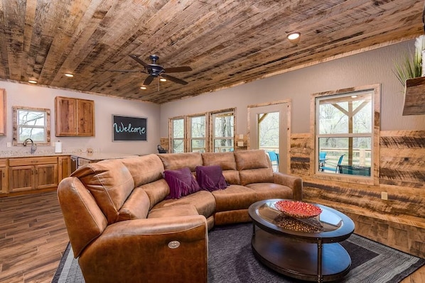 A spacious living room with a leather sectional sofa, a coffee table, and a ceiling fan.