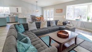 A modern living room with a sectional sofa, a coffee table, and a dining area with a table and chairs. - Spacious & Secluded Mountain Retreat by Bryce Resort: Ski, Mtn Bike, Game room (Basye)
