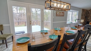 A dining area with a wooden table set for four, black chairs, and a view of the backyard through glass doors. - Spacious & Secluded Mountain Retreat by Bryce Resort: Ski, Mtn Bike, Game room (Basye)