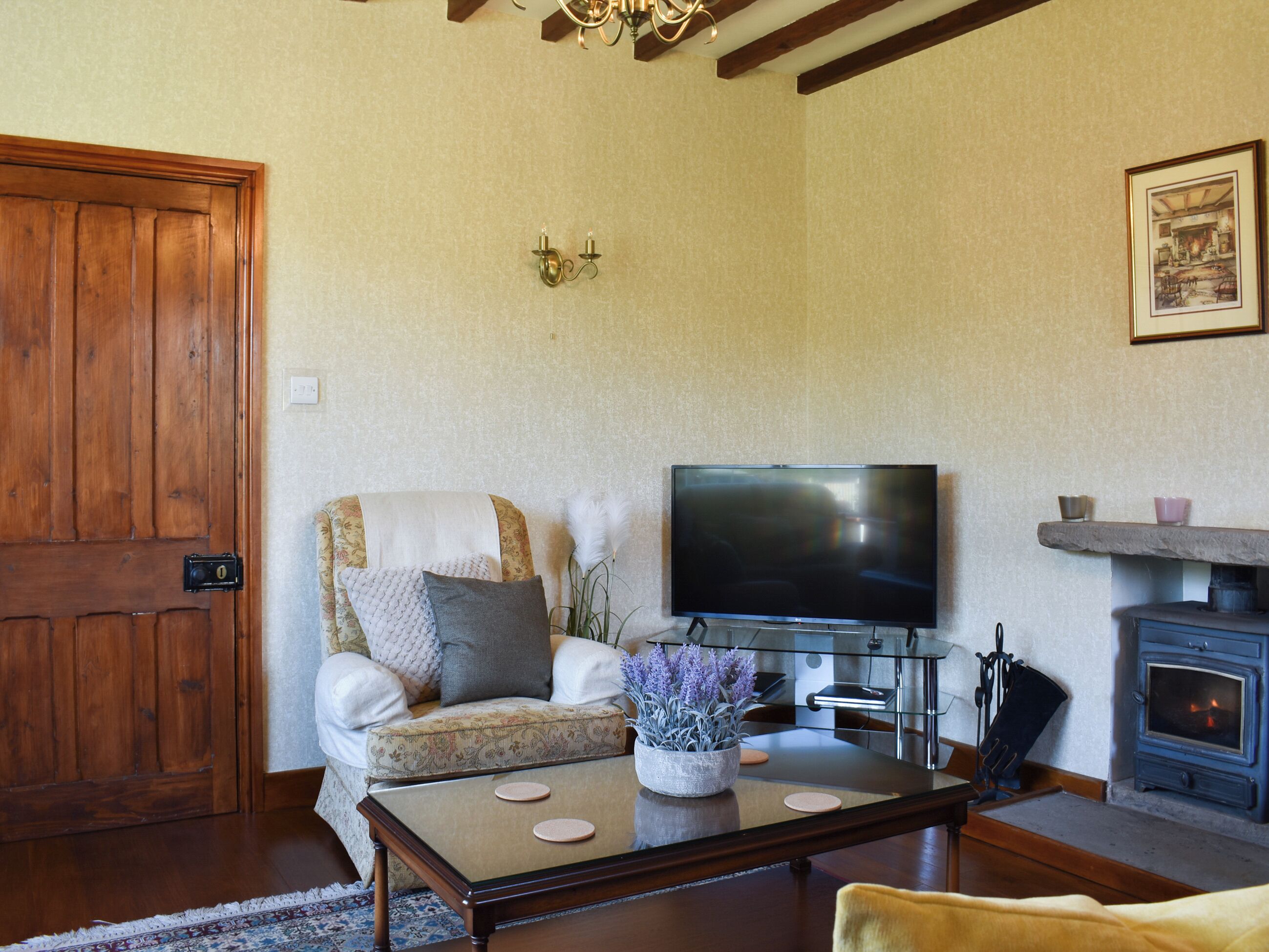 A living room with a wooden door, a sofa with cushions, a flat-screen TV, a fireplace, and a coffee table.