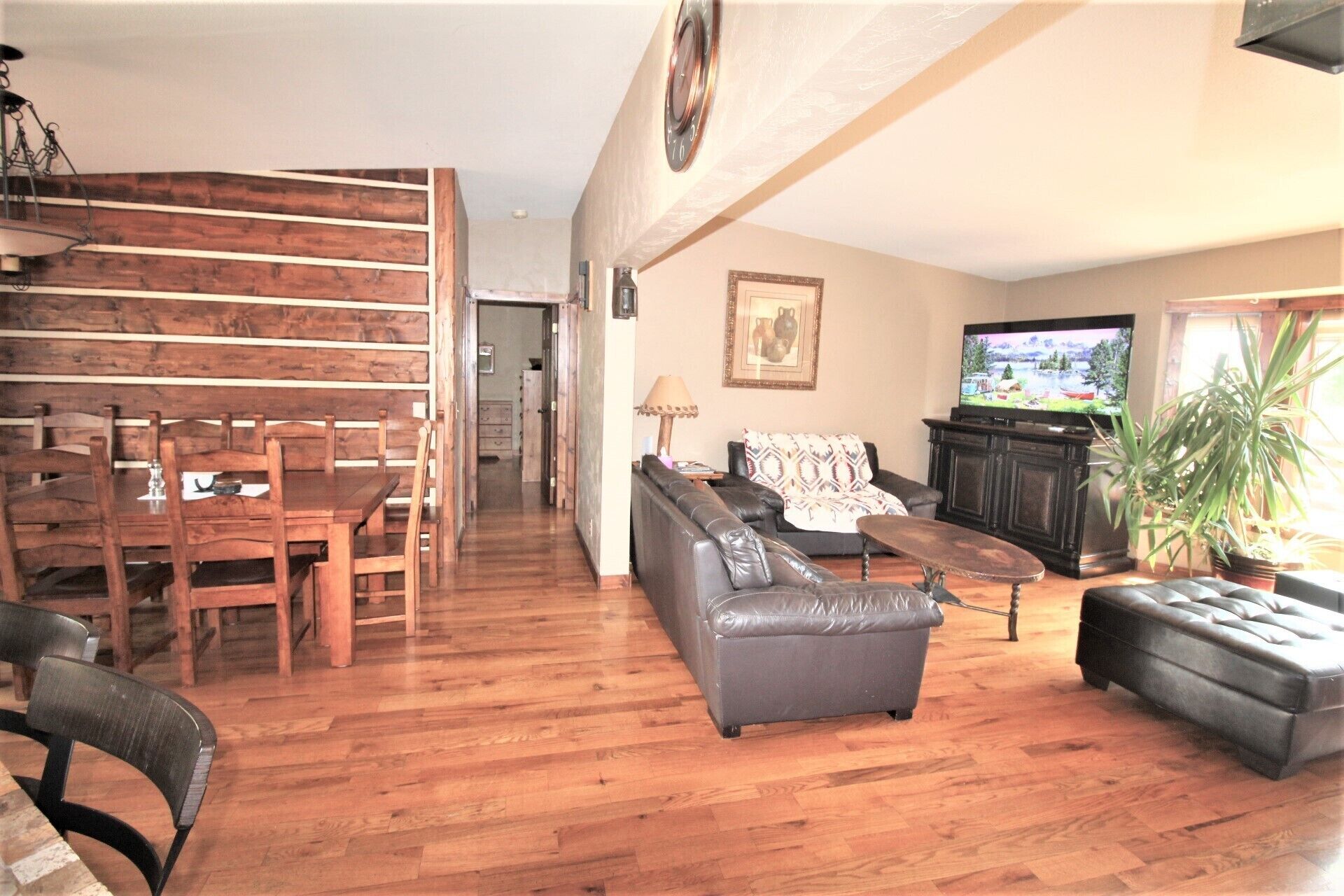 Ein Wohnzimmer mit einem Holzesstisch, einer Ledersofa und einem Fernseher.