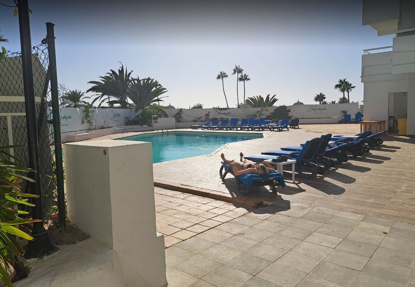 A pool area with lounge chairs and palm trees.