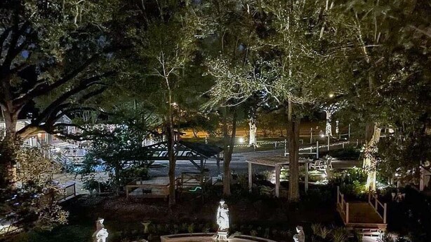 A nighttime garden with statues, a fountain, and a well-lit pathway. - Marguerite Bed and Breakfast (St. Gabriel)