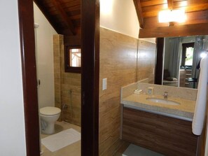 A bathroom with a toilet, shower, and sink.