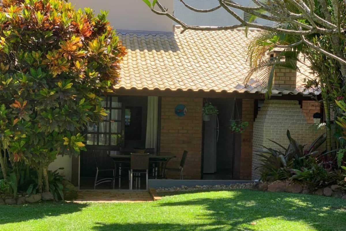 A house with a tiled roof, a patio with a table and chairs, and a well-maintained lawn.