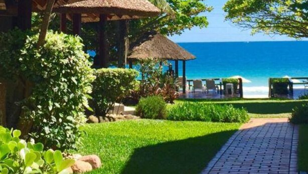 A resort with thatched-roof structures, a paved walkway, and a view of the ocean. - Pousada Solar dos Girassóis (Bombinhas)