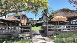 A beachside resort with wooden walkways, thatched-roof structures, and a sign reading "Solar dos Girassóis". - Pousada Solar dos Girassóis (Bombinhas)