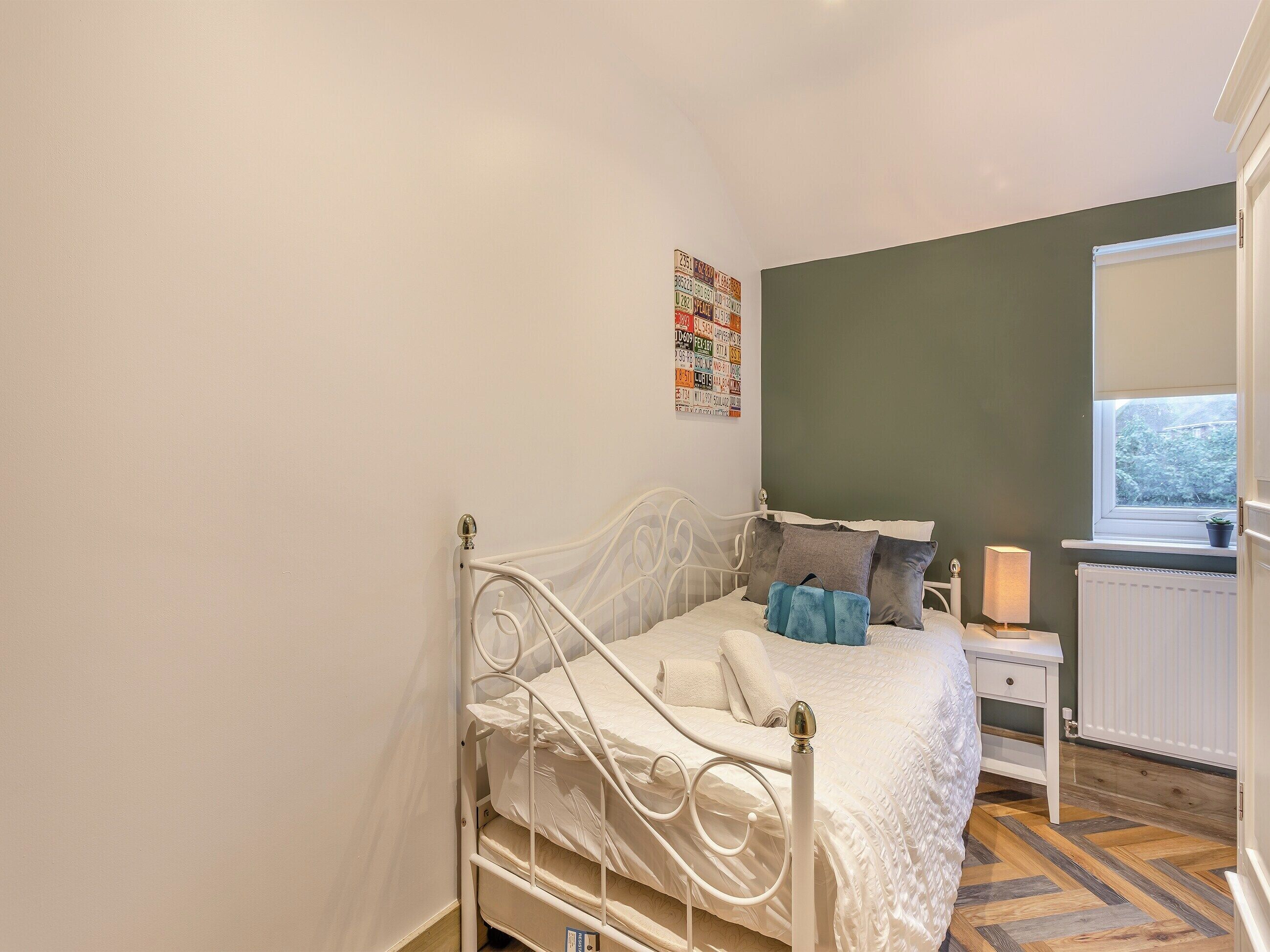 A bedroom with a bed, a nightstand, a window, and a radiator.