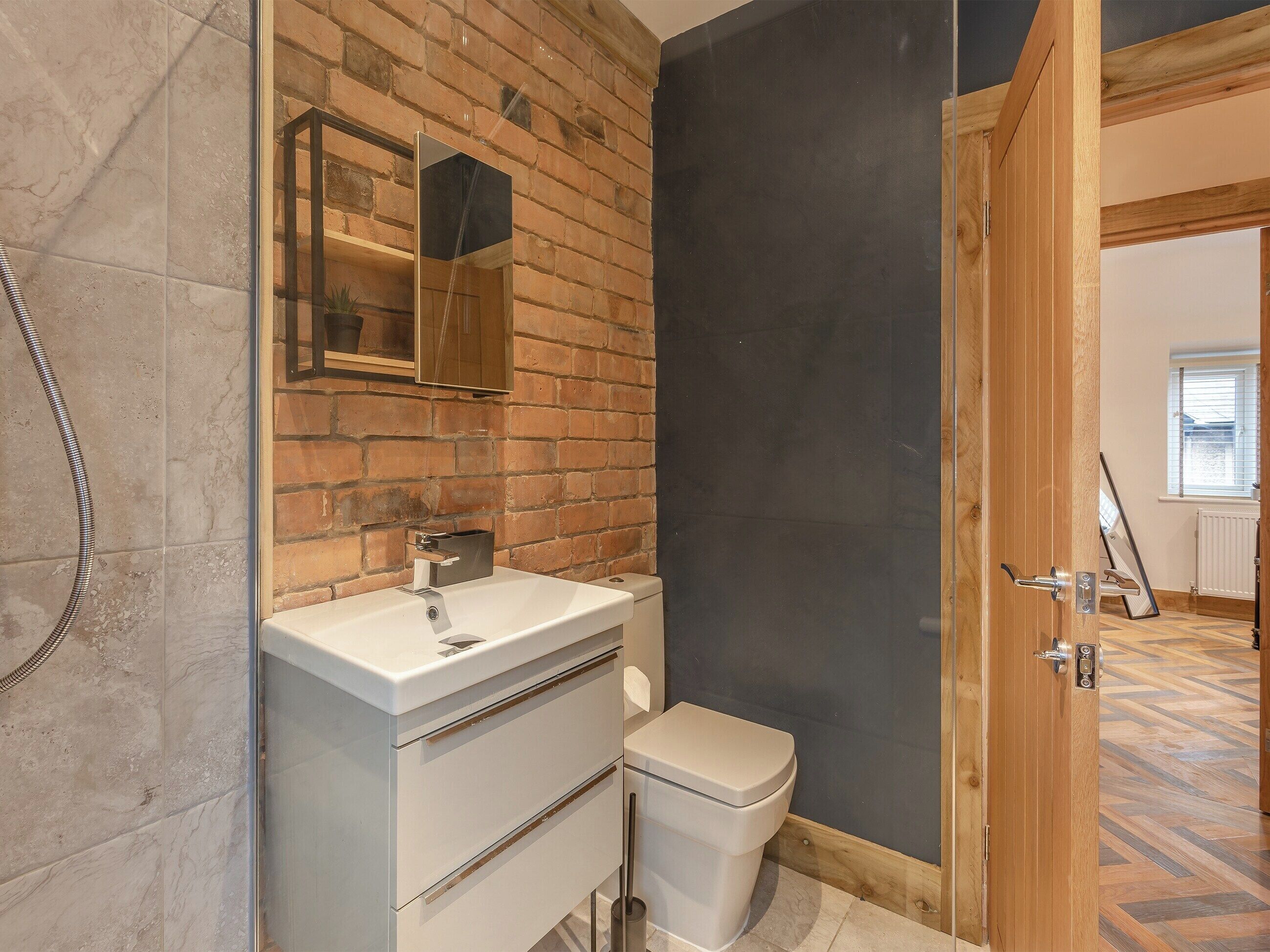 A bathroom with a white sink, a mirror, a toilet, and a shower area.
