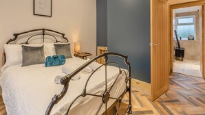 Ein Schlafzimmer mit einem Metallbettgestell, einem Nachttisch mit Lampe und Blick auf einen Balkon durch eine offene Tür.