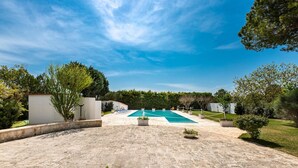 A stone patio leading to a swimming pool with a clear blue sky above. - 2920 Villa Oasis by Perle di Puglia (Mottola)