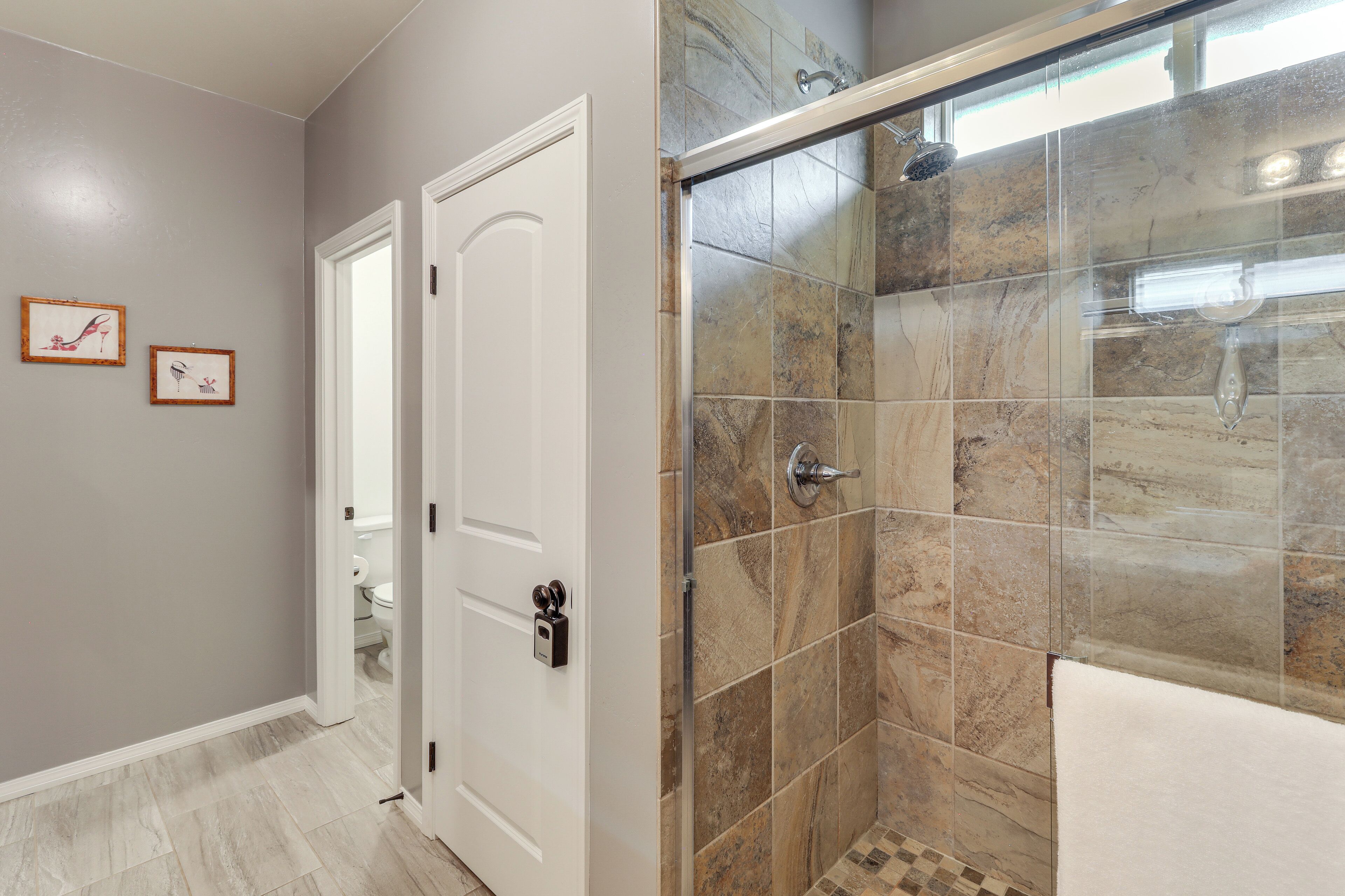 A bathroom with a shower, tiled walls, and a white door.