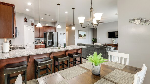 A modern kitchen with a central island, bar stools, and a dining table with placemats. - Ski, Hike & Explore: Bellemont Home w/ Fenced Yard (Bellemont)