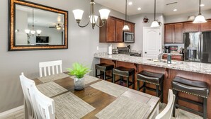 A modern kitchen with wooden cabinets, a granite countertop, and stainless steel appliances. There is a dining area with a wooden table and chairs, and a large mirror above the table. - Ski, Hike & Explore: Bellemont Home w/ Fenced Yard (Bellemont)
