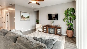 A living room with a gray sectional sofa, a wooden coffee table, a ceiling fan, a flat-screen TV, and a large potted plant. - Ski, Hike & Explore: Bellemont Home w/ Fenced Yard (Bellemont)
