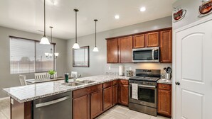A modern kitchen with granite countertops, stainless steel appliances, wooden cabinets, and pendant lighting. - Ski, Hike & Explore: Bellemont Home w/ Fenced Yard (Bellemont)