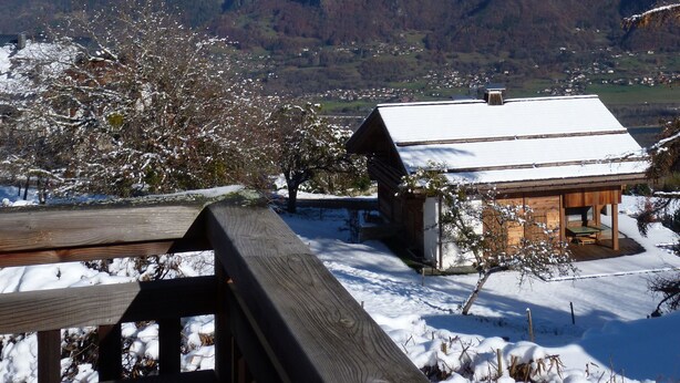 Ein Berg mit schneebedeckten Gipfeln und eine Holzhütte mit verschneitem Dach.