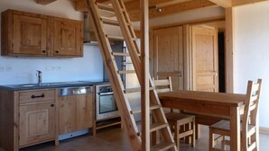 Eine Küche mit Holzausstattung, einem eingebauten Backofen und einer Holzlade.