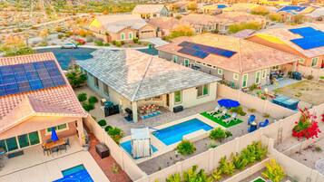 A residential area with houses featuring solar panels, a swimming pool, and outdoor seating areas.