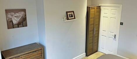 A bedroom with a bed, a dresser, a wardrobe, and a framed picture on the wall.
