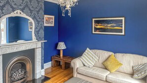 A living room with a fireplace, a sofa, a lamp, and a chandelier. - 3 bedroom accommodation in Tynemouth (Tynemouth)