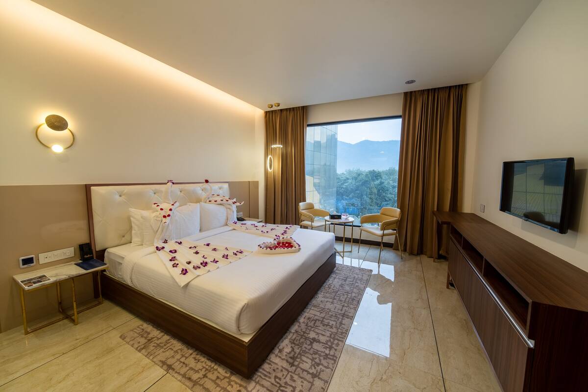Habitación de hotel moderna con una cama grande, televisión, escritorio y vistas a la montaña.