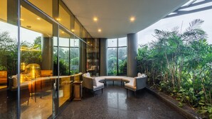 Un interior moderno con paredes de vidrio, una zona de estar curvada y vistas a un follaje exuberante.
