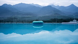 Una piscina con un flotador, rodeada de montañas y un cielo despejado.