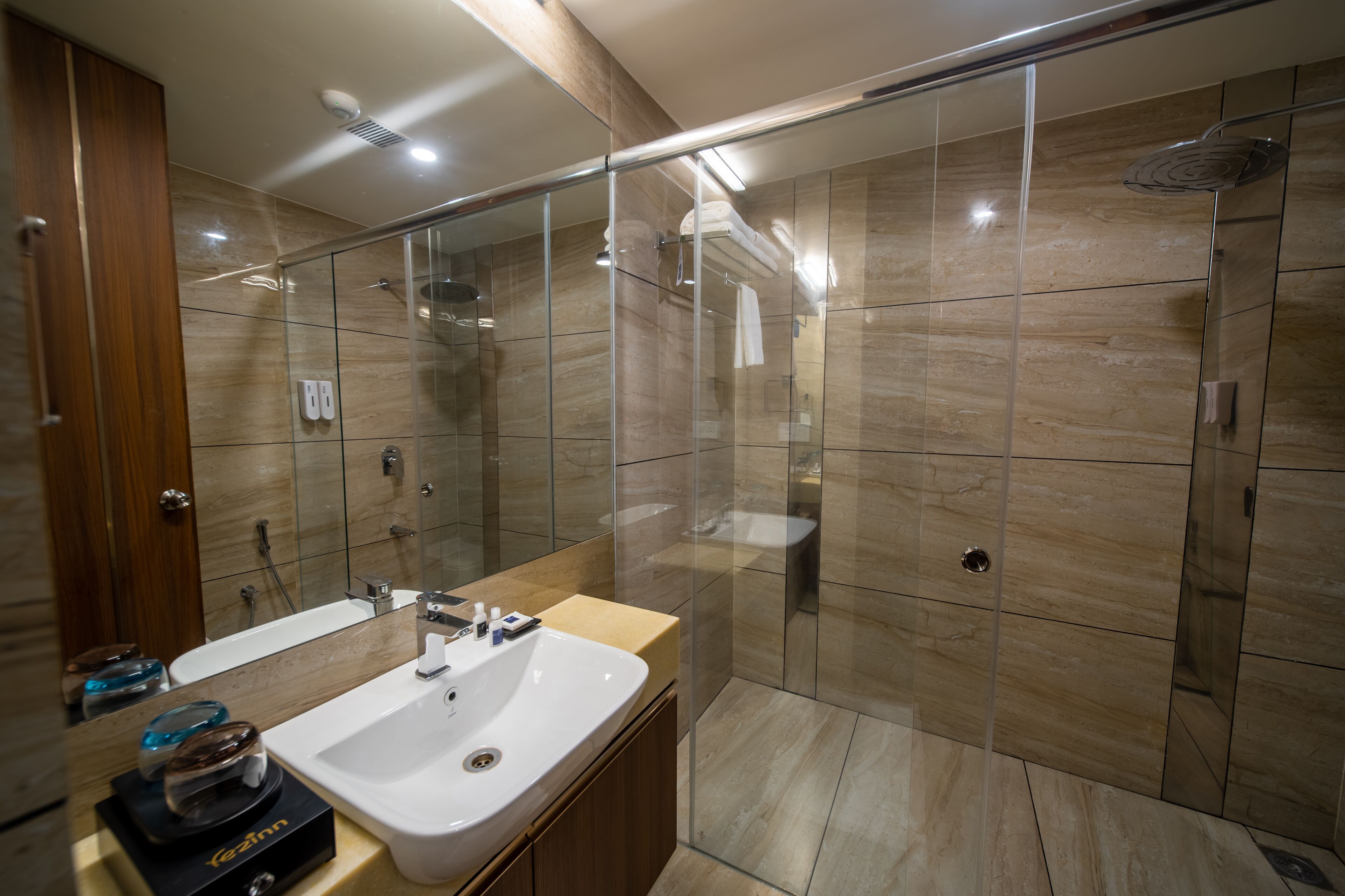 A modern bathroom with a glass-enclosed shower, a double sink vanity, and a large mirror.