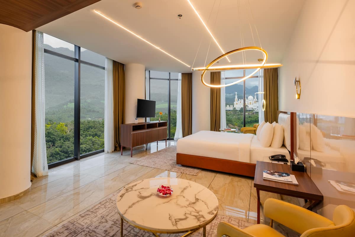 Habitación de hotel moderna con una cama grande, un escritorio, un televisor y vistas a la ciudad.