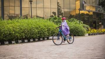 A person riding a bicycle on a paved path with a modern building in the background.